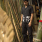 Soham in an embroidered black linen shirt standing in a bamboo shop