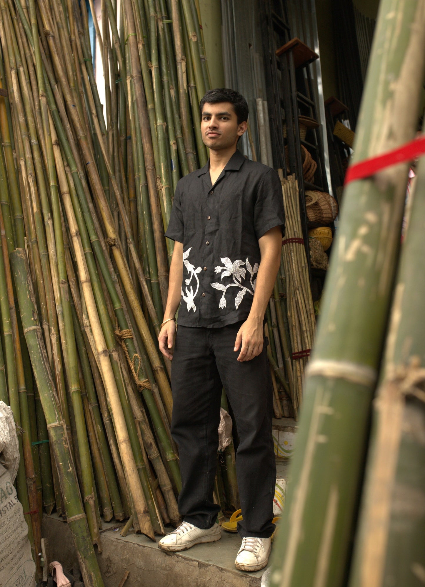 Zoomed in Side details of Soham in a black linen shirt standing in a bamboo shop