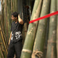 Side details of Soham in a black linen shirt standing in a bamboo shop