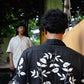 Back of a black linen half sleeved shirt with off-white floral embroidery throughout