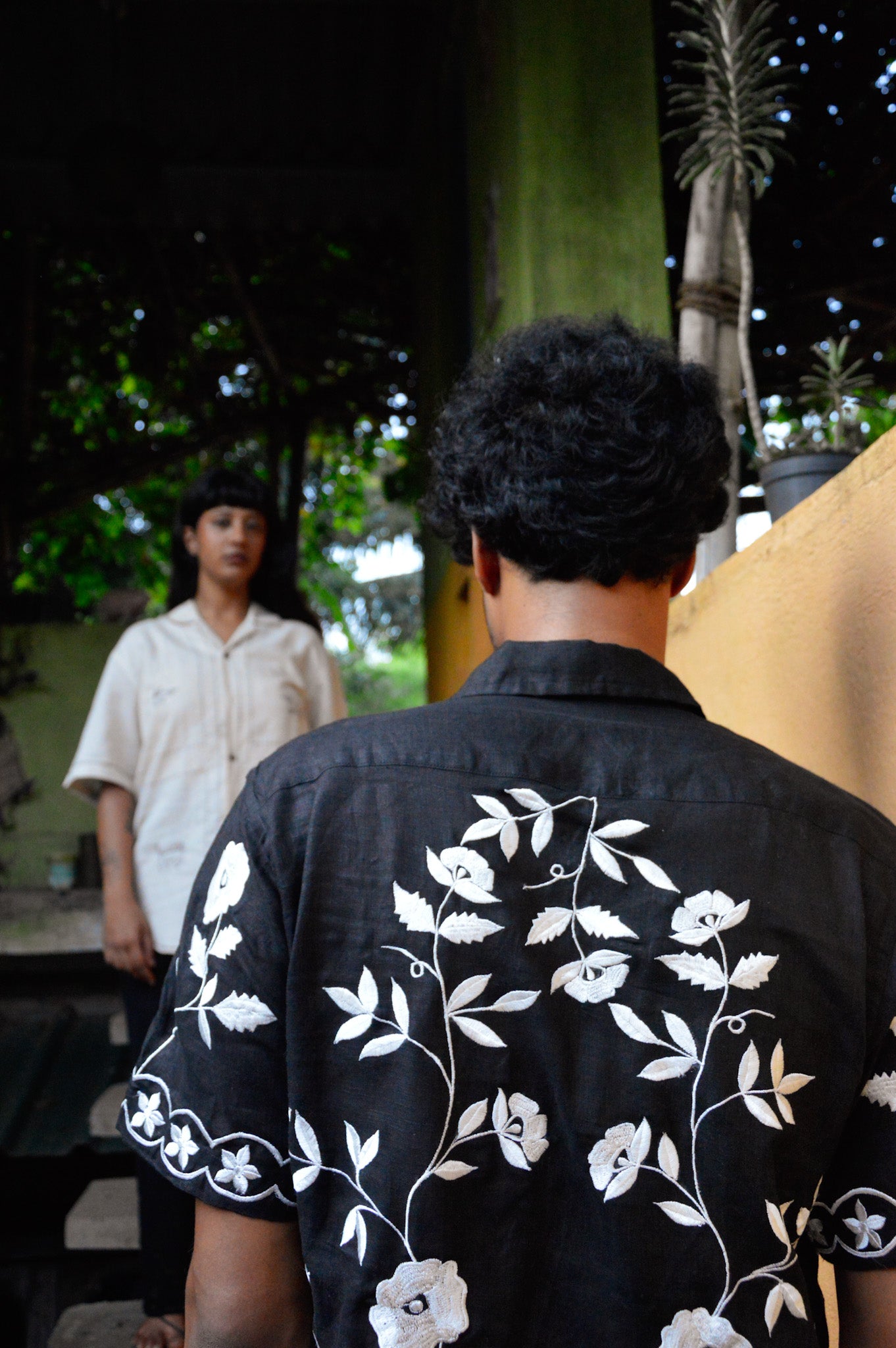 Back of a black linen half sleeved shirt with off-white floral embroidery throughout