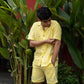 a Front view of a man wearing co-ordinated pair of yellow linen shirt and shorts with green sun embroidery and green border on the sleeves.