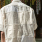 Back of a young man in an off-white half-sleeved shirt made with patches of cotton and linen squares