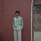 A man in mint-green pure linen full-sleeved shirt is standing in front of a pink wall