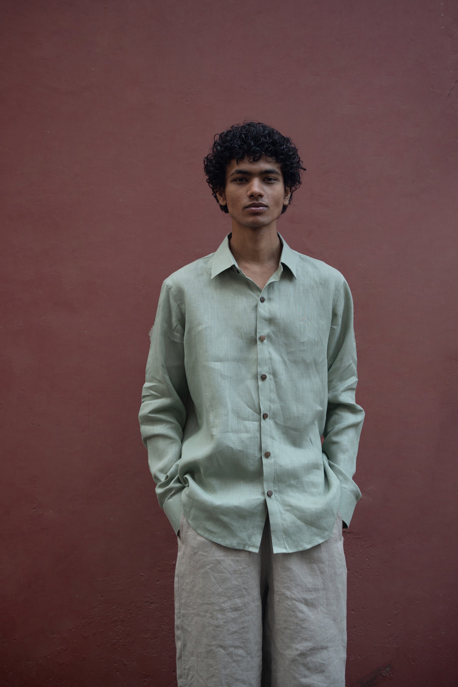 Closer look of a man in mint-green pure linen full-sleeved shirt is standing in front of a pink wall