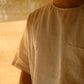 A man in offwhite pure linen t-shirt featuring a left pocket standing in soft light