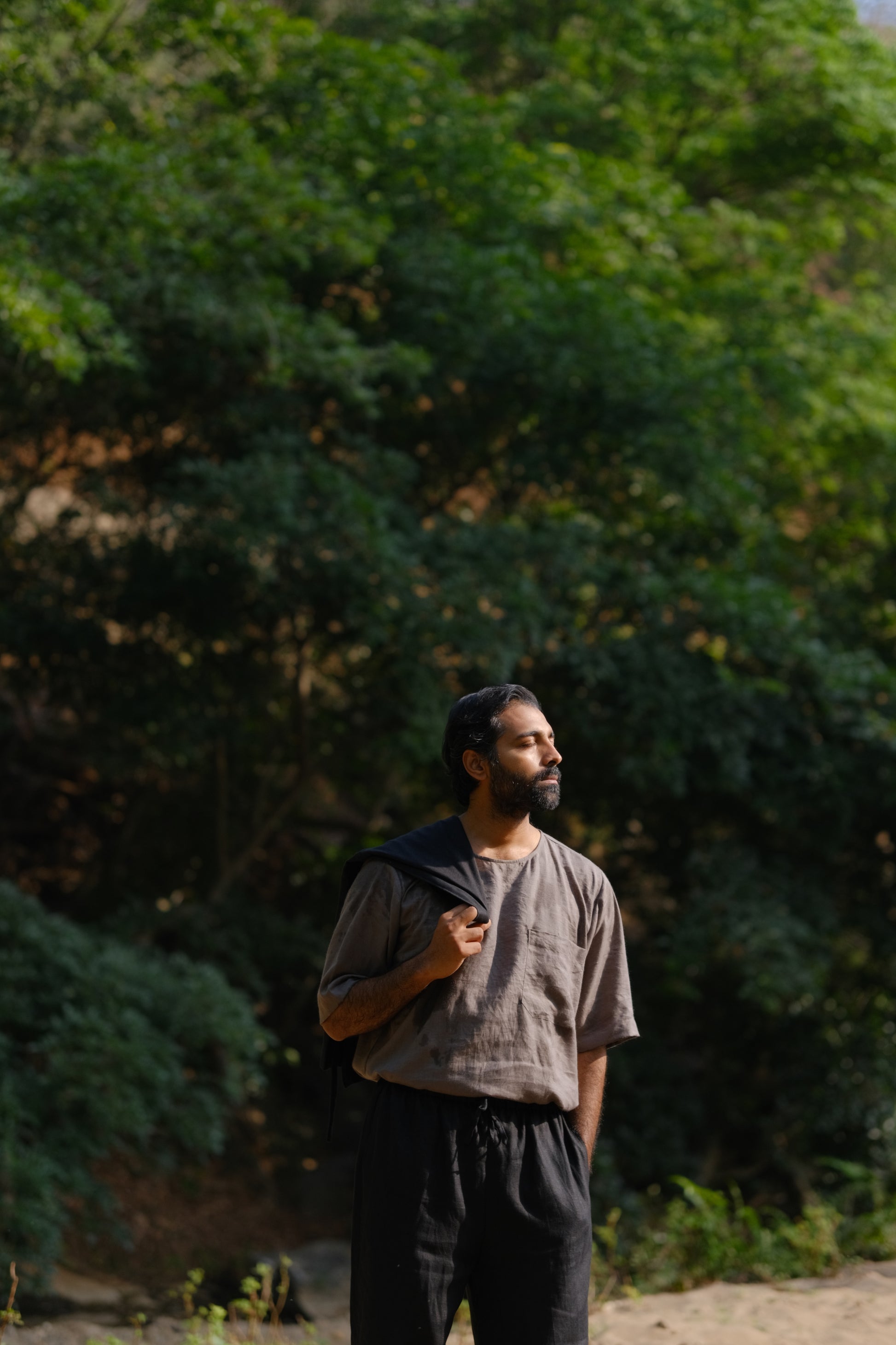 closer look of a man in a grey linen T-shirt standing in a field