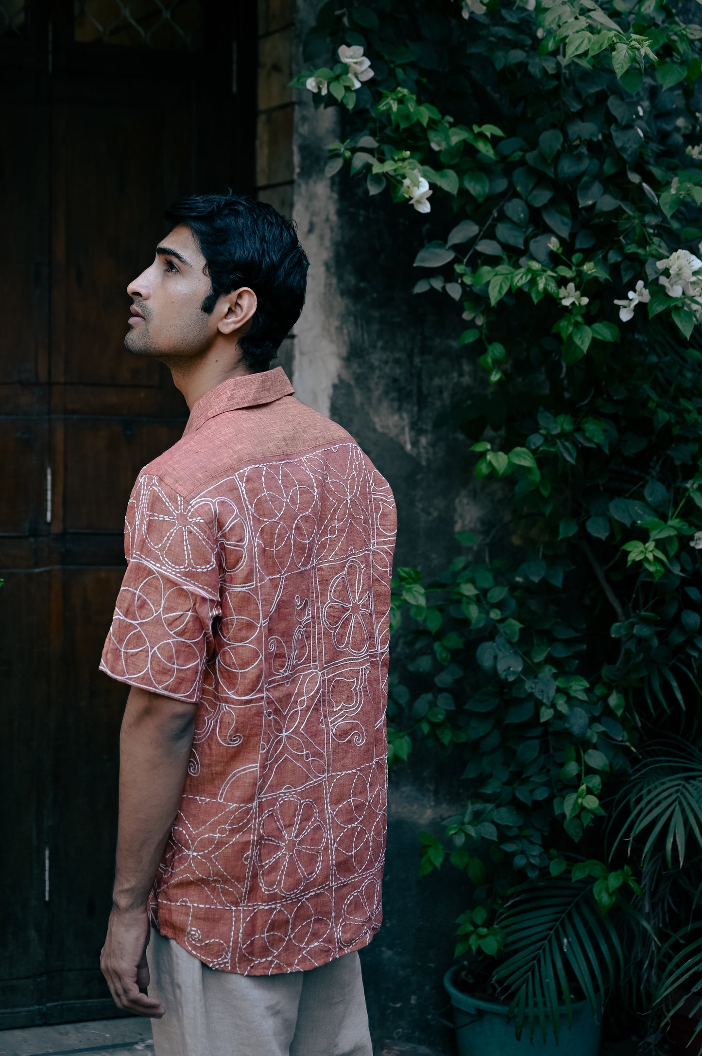 back detail of a burnt orange linen shirt hand-embroidered in the grid pattern of terracotta tiles