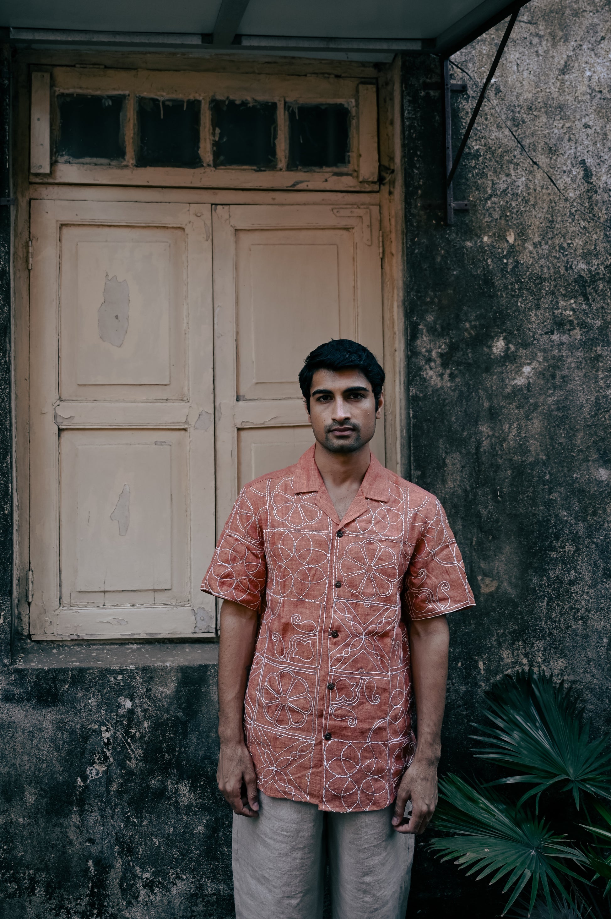 A young man in a burnt orange hand-embroidered linen shirt 