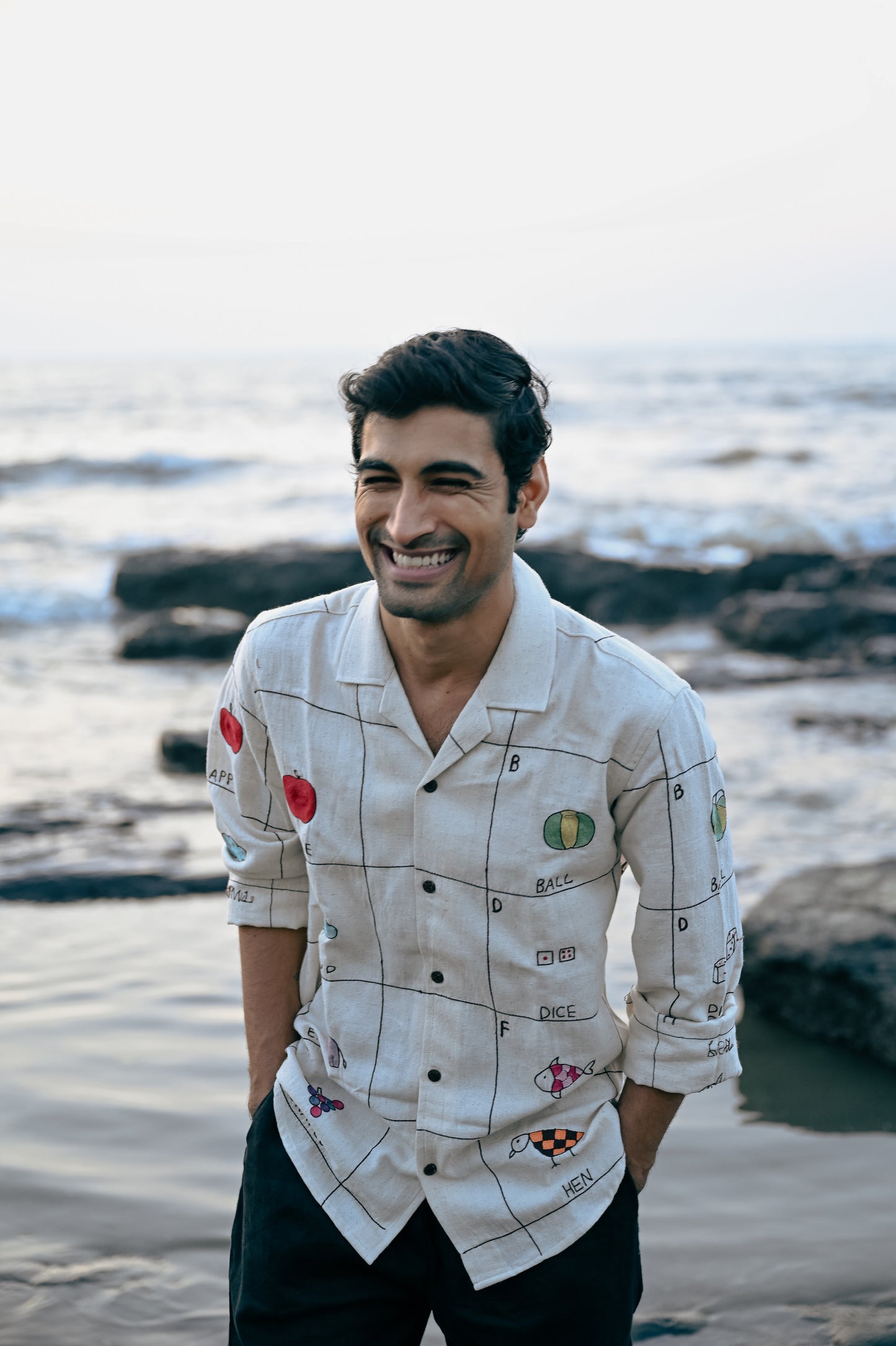 A young man in an beige linen full-sleeved shirt with the hand-embroidered alphabet