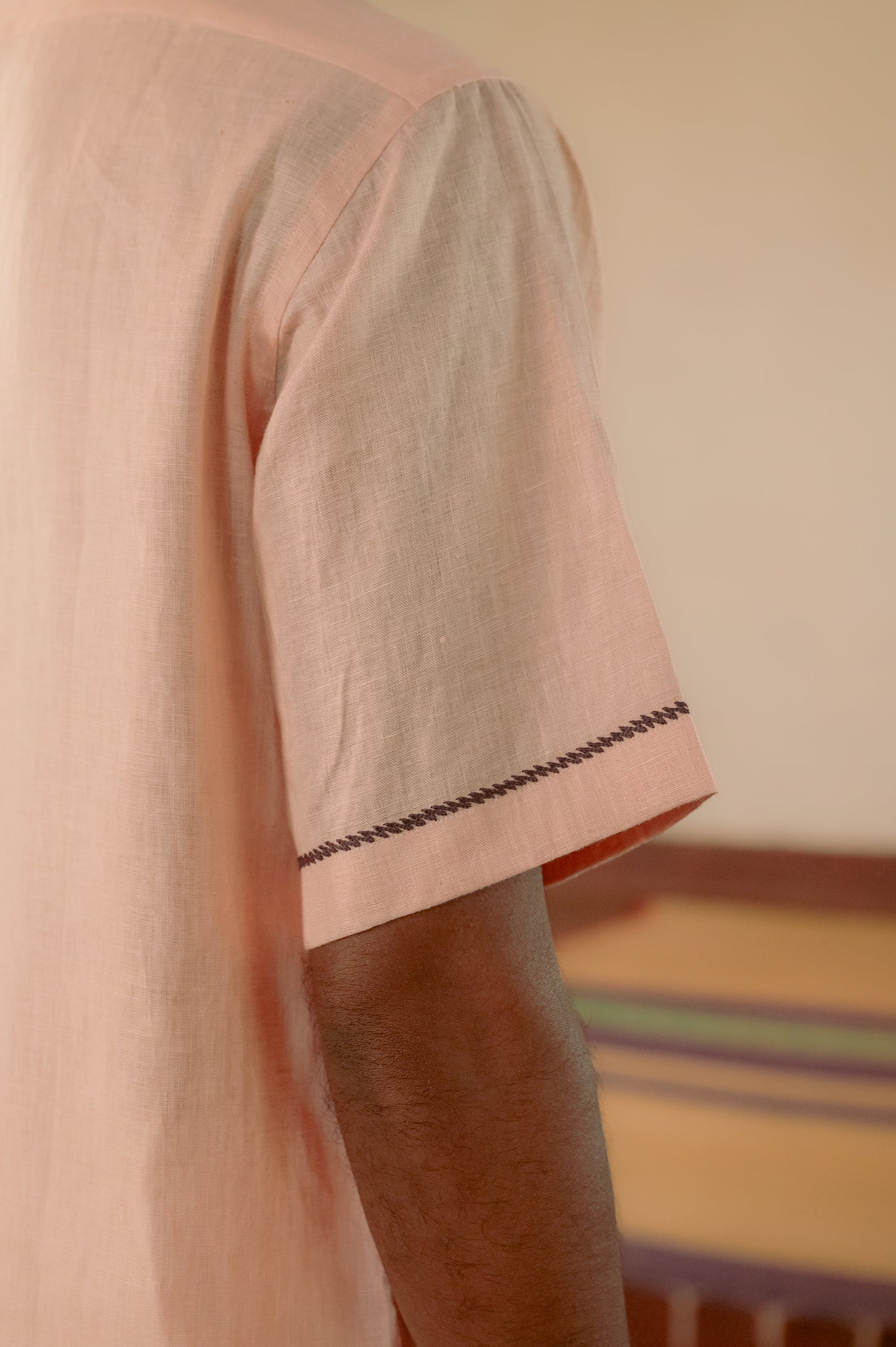 Zoomed in shot of the embroidered border on the sleeves of a linen peach shirt