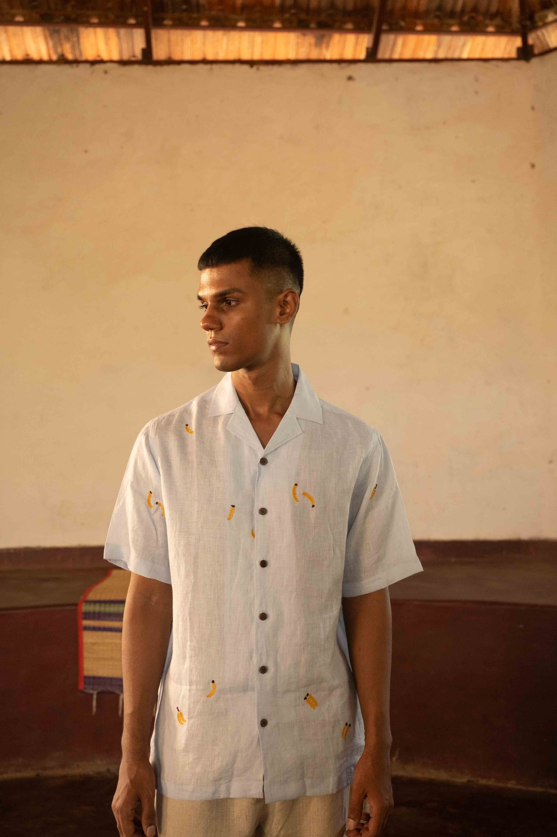 A man in eco-friendly, monkey business hand-embroidered linen shirt in a yoga hall. half sleeves shirt, Material: linen, front view