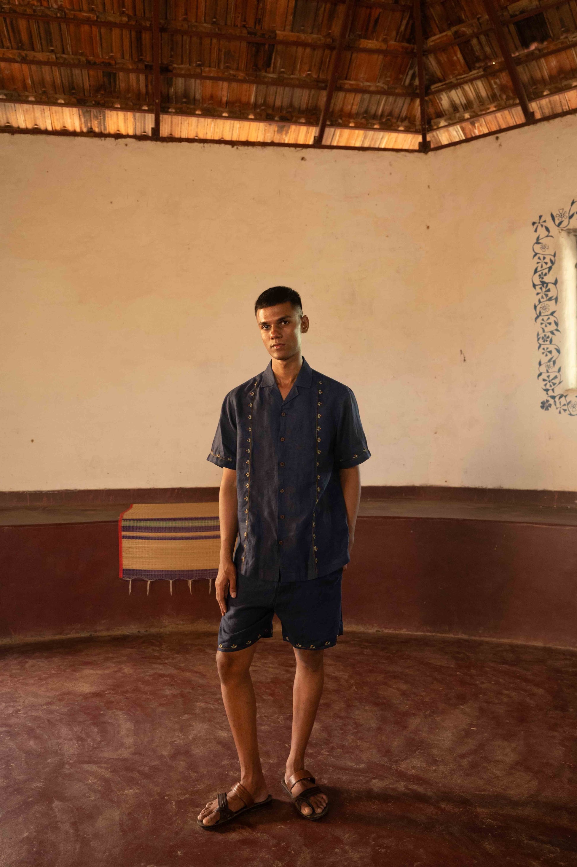 A man in eco-friendly, buds in blue hand-embroidered linen shirt in a yoga hall. half sleeves shirt, Material: linen, front view