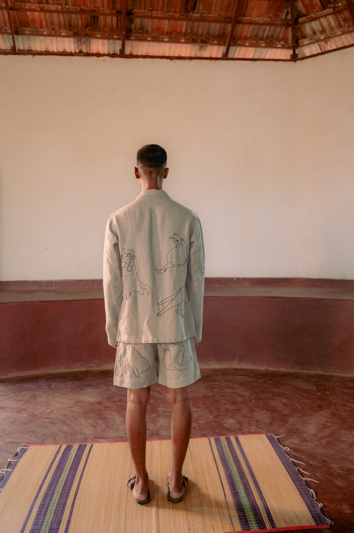 A man in eco-friendly, Cats hand-embroidered linen shirt in a yoga hall. Full sleeve shirt, Material: linen, Back view