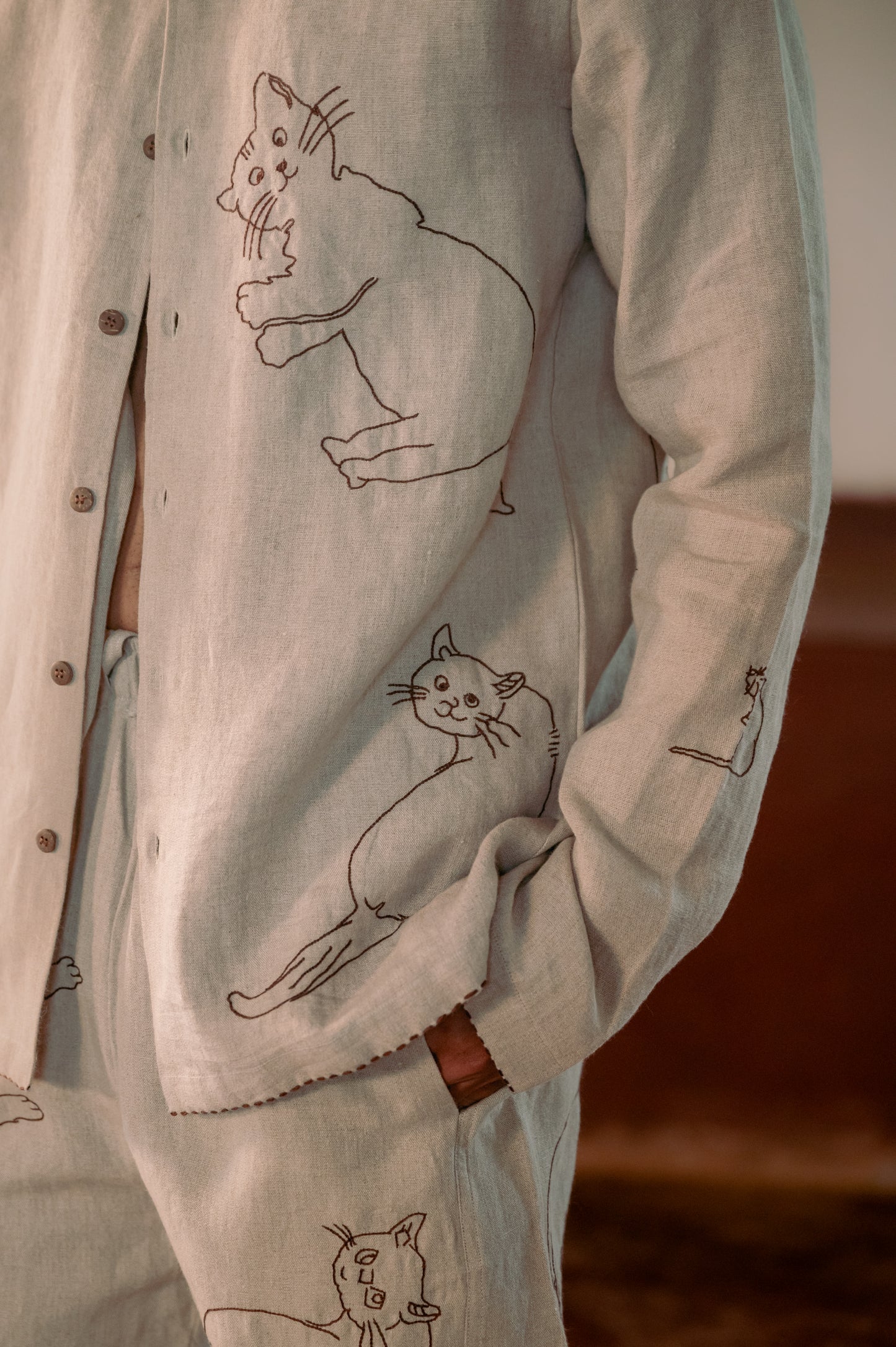 A detailed left view of a man in eco-friendly, Cats hand-embroidered linen shirt. Full sleeve shirt, Material: linen.