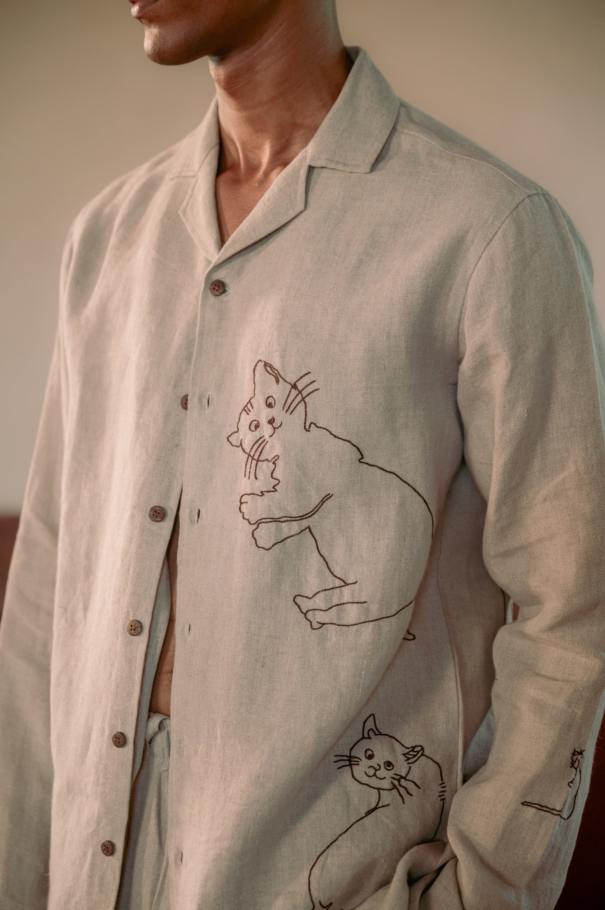 A detailed view of a man in eco-friendly, Cats hand-embroidered linen shirt. Full sleeve shirt, Material: linen.