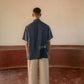 man in a blue linen shirt hand-embroidered with different loops standing in a yoga hall. Half sleeve shirt, Material: linen, Back view