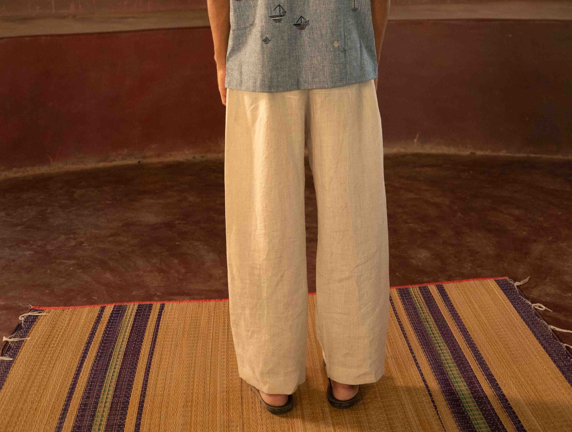 Back view of a man standing in a yoga hall  wearing beige linen lounge pants.