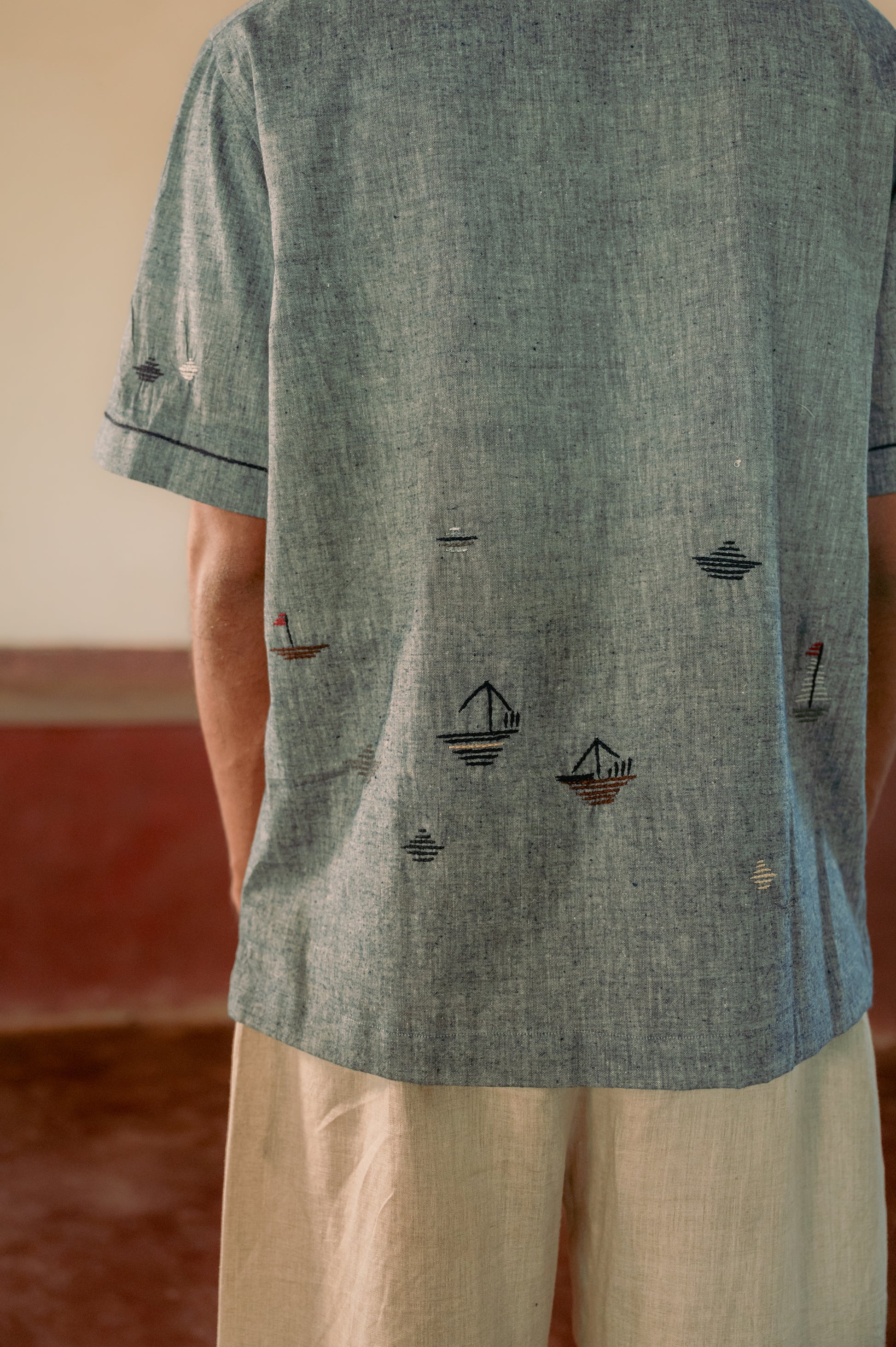 Back of the man in organic cotton shirt with boats and ships embroidered in the lower half of the shirt. Half sleeve shirt, Material: cotton, Back view