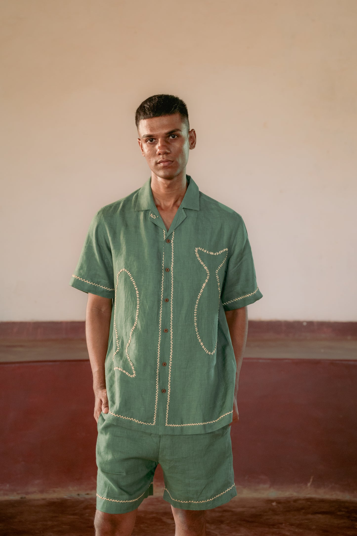 man in eco-friendly Green fish hand-embroidered  linen shirt standing in a yoga hall. Half sleeve shirt, Material: linen, Front view