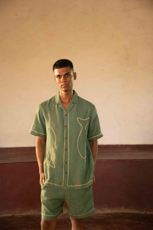 Front view of green linen shorts with hand-embroidered fishes.