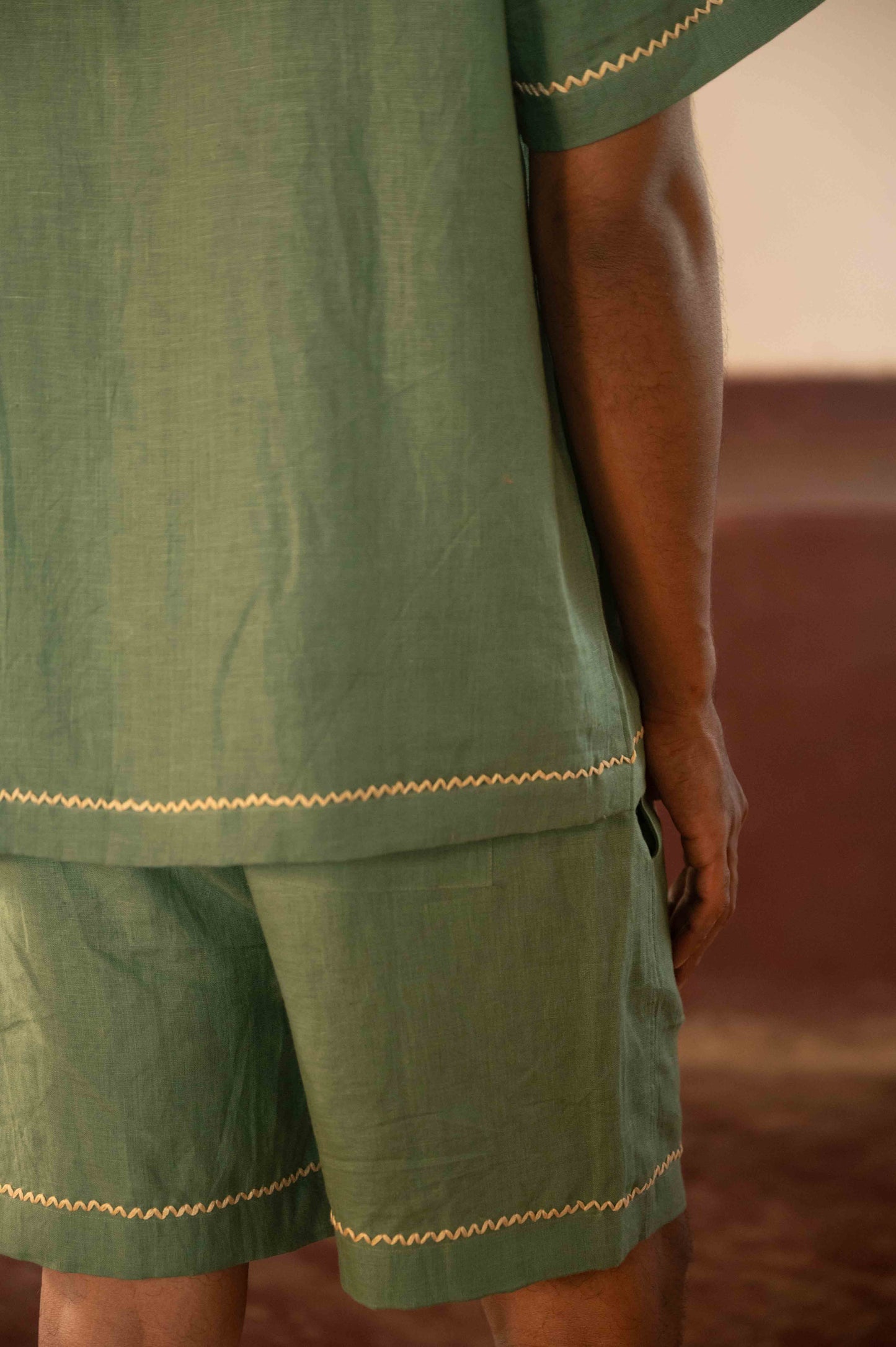 Back view of green linen shorts with hand-embroidered border.