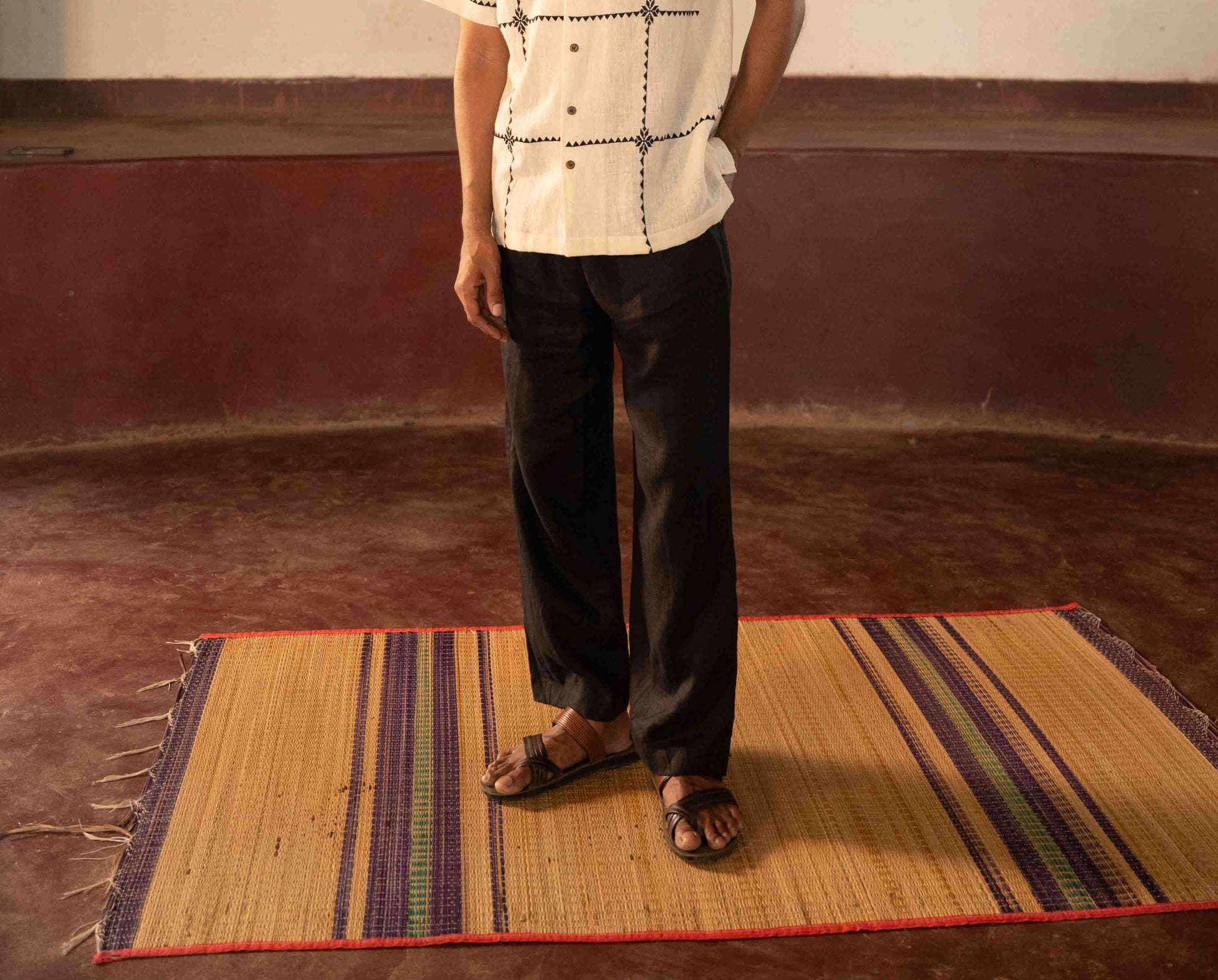 A man standing in a yoga hall wearing black linen lounge pants. Front view