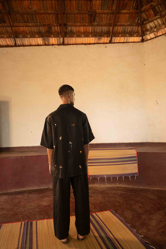 A man in eco-friendly, wild sprigs hand-embroidered linen shirt in a yoga hall. half sleeves shirt, Material: linen, back view