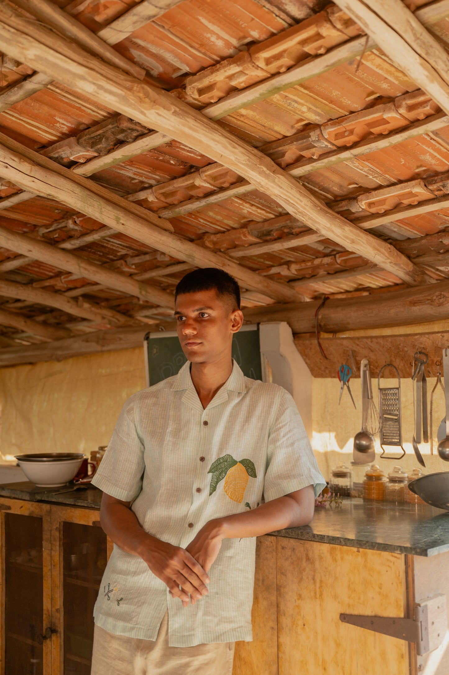 a man in the kitchen wearing green and white stripes mango embroidered linen shirt. Front view