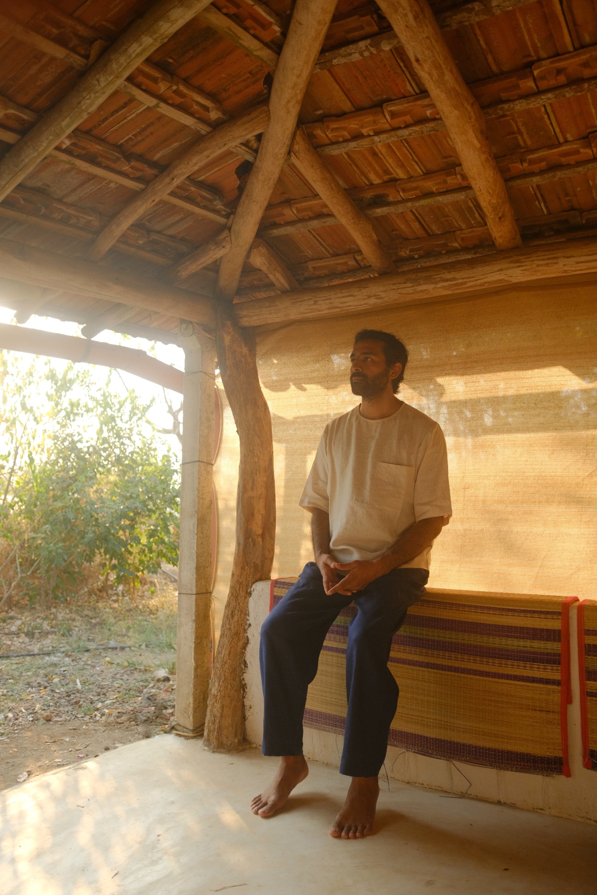 A man in off-white pure linen T-shirt sitting in a rustic resort