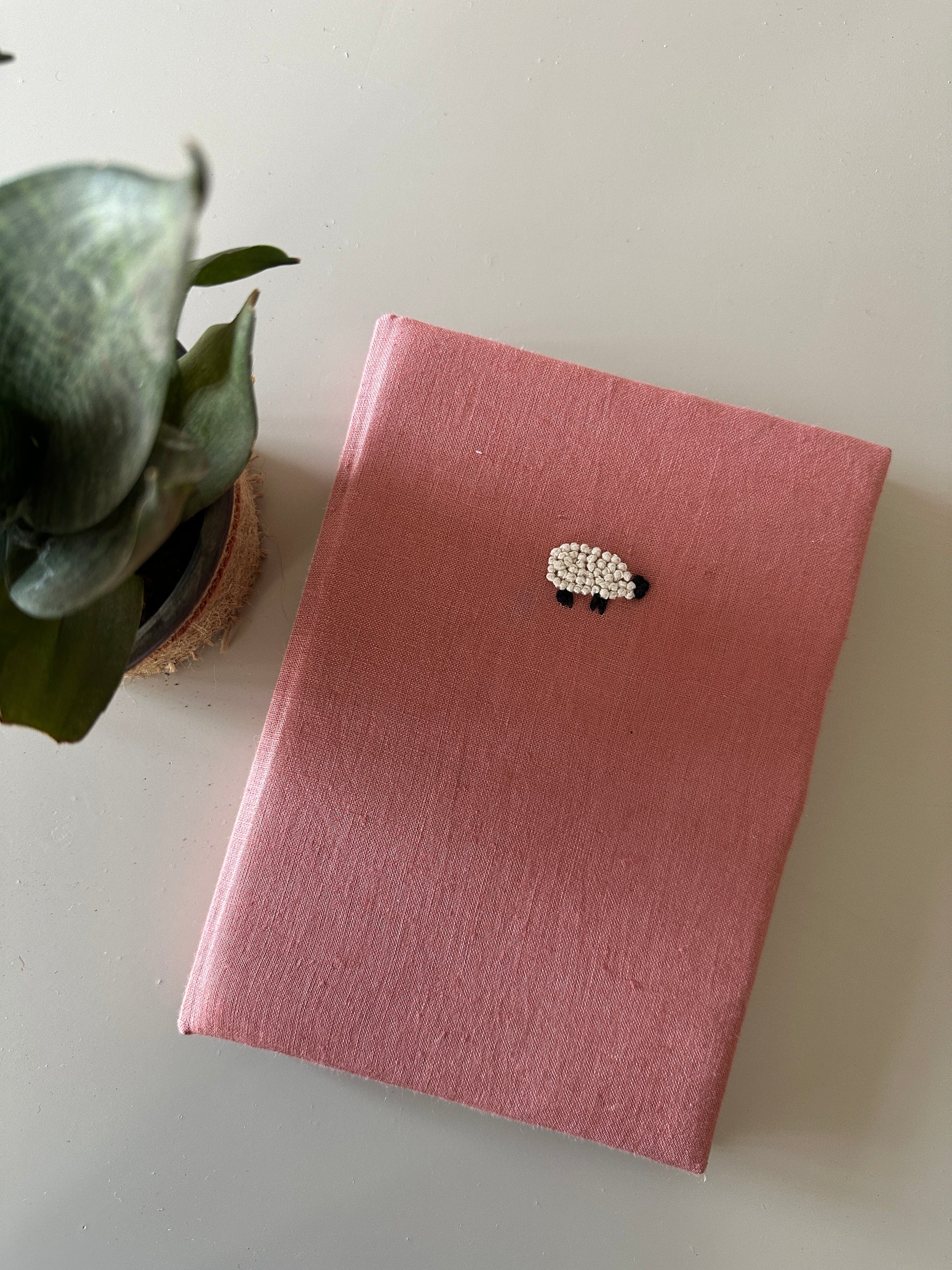 A peach cover diary made with peach linen scraps with a white sheep embroidered on the cover