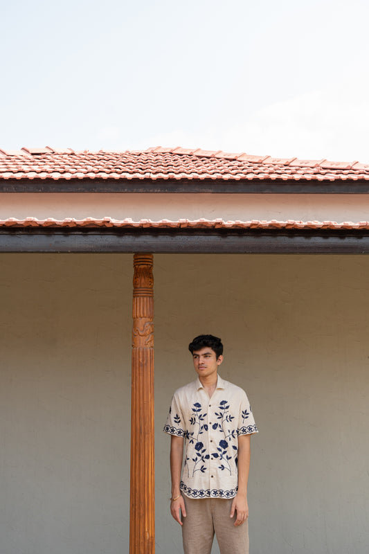 a man wearing beige linen blue floral hand embroidered shirt.