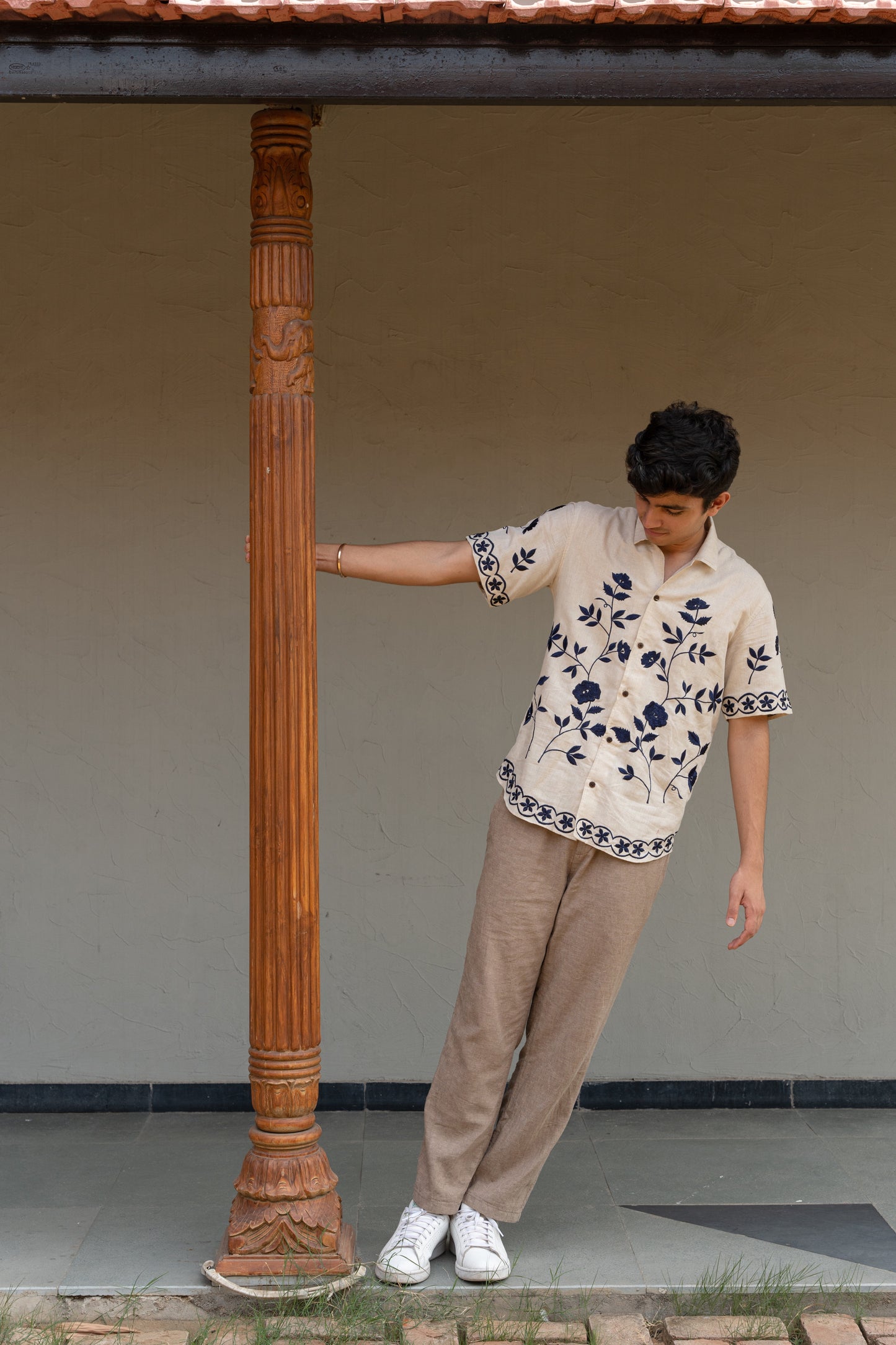 a man wearing beige linen blue hand-embroidered flora shirt 