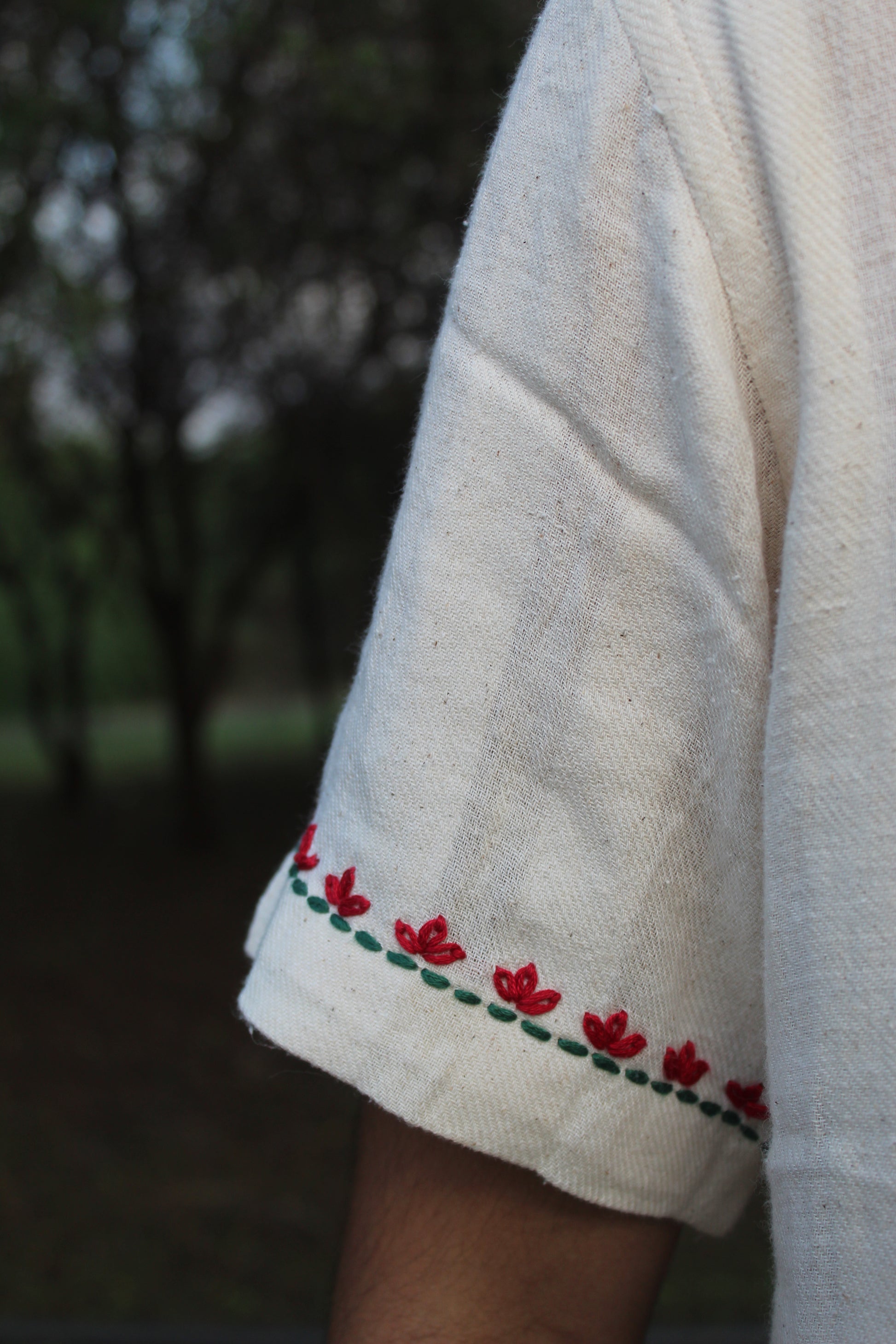 Details of the lotus embroidered sleeves of an off-white cotton shirt