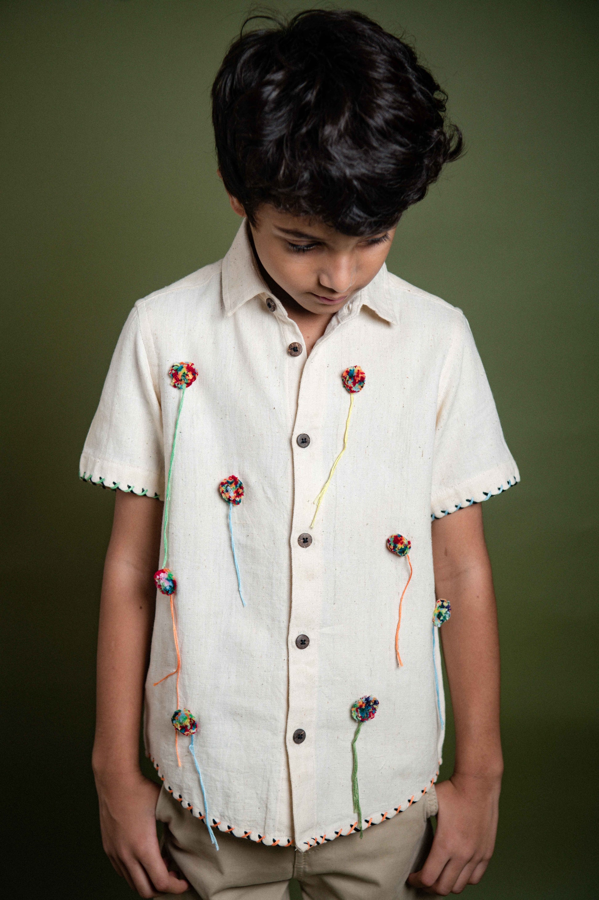 Details of a kala cotton half-sleeved shirt with pom poms embroidered through out 