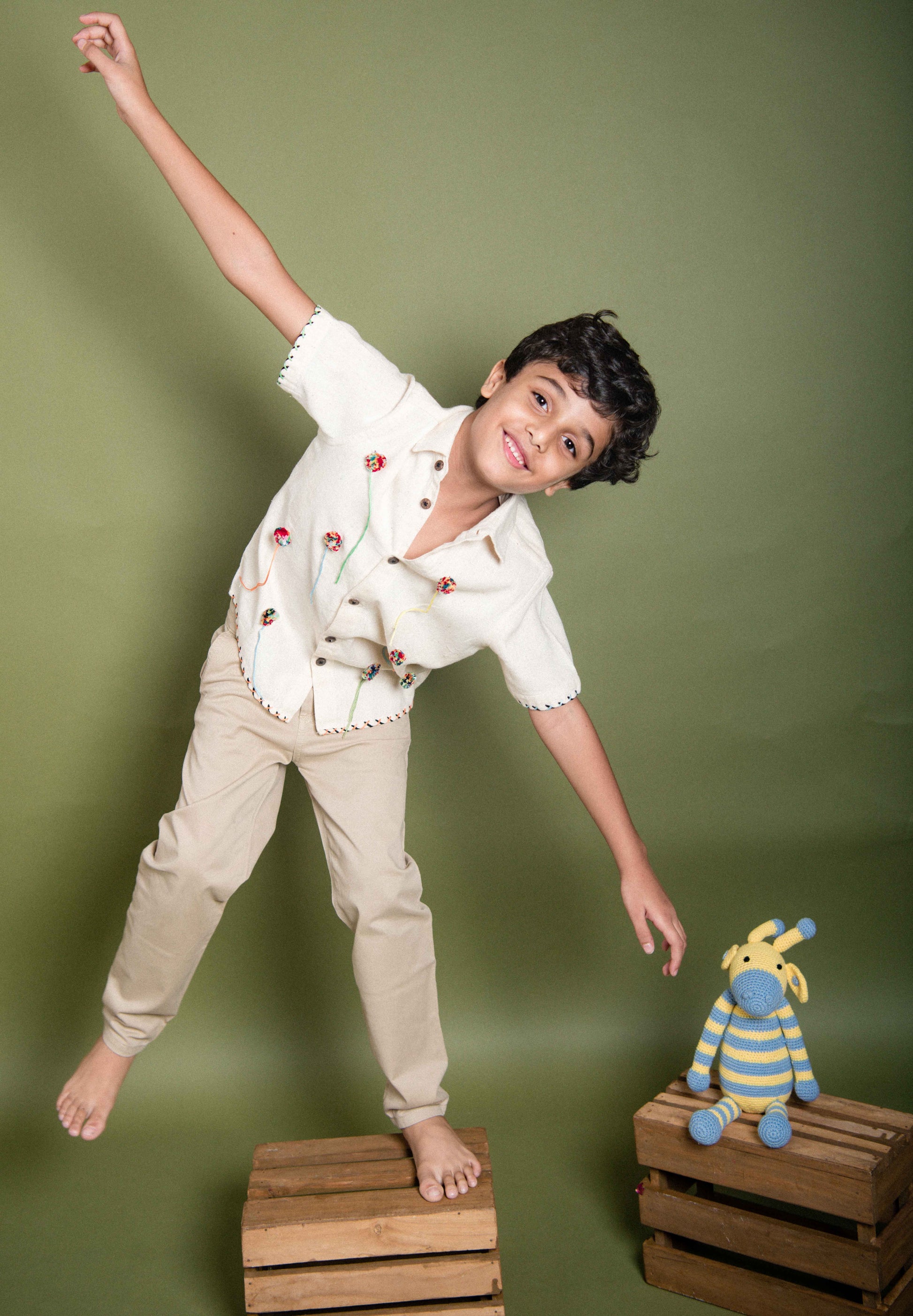 A 6 year old kid goofing in our kala cotton half-sleeved shirt with pom poms embroidered through out