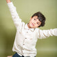 A young 7-8 year old boy in an off-white linen full sleeved shirt with small sheep embroidered throughout 