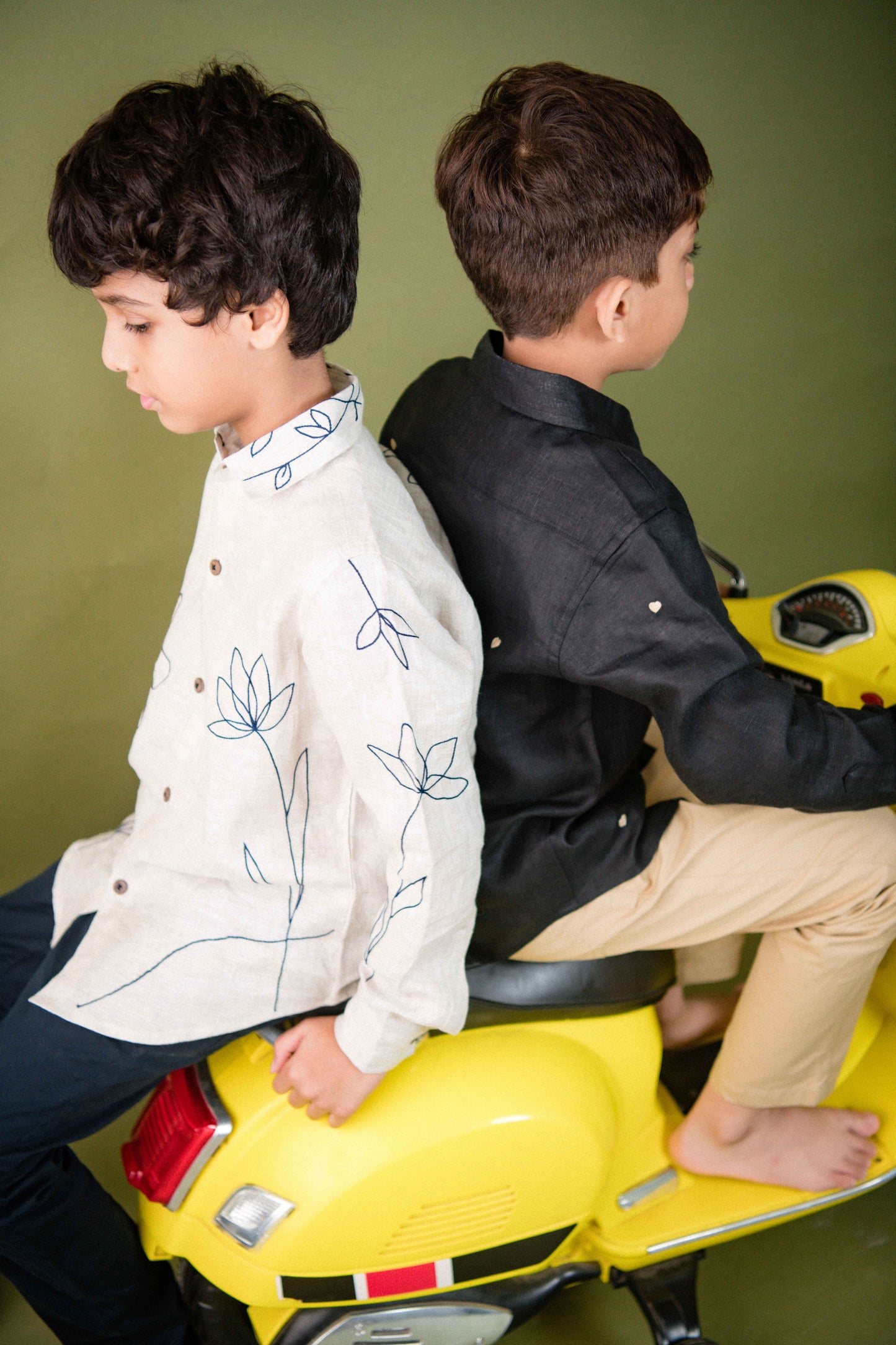 A focus on the sleeve detail of a 5-6 year old boy in a full sleeved floral embroidered shirt sitting on a scooter