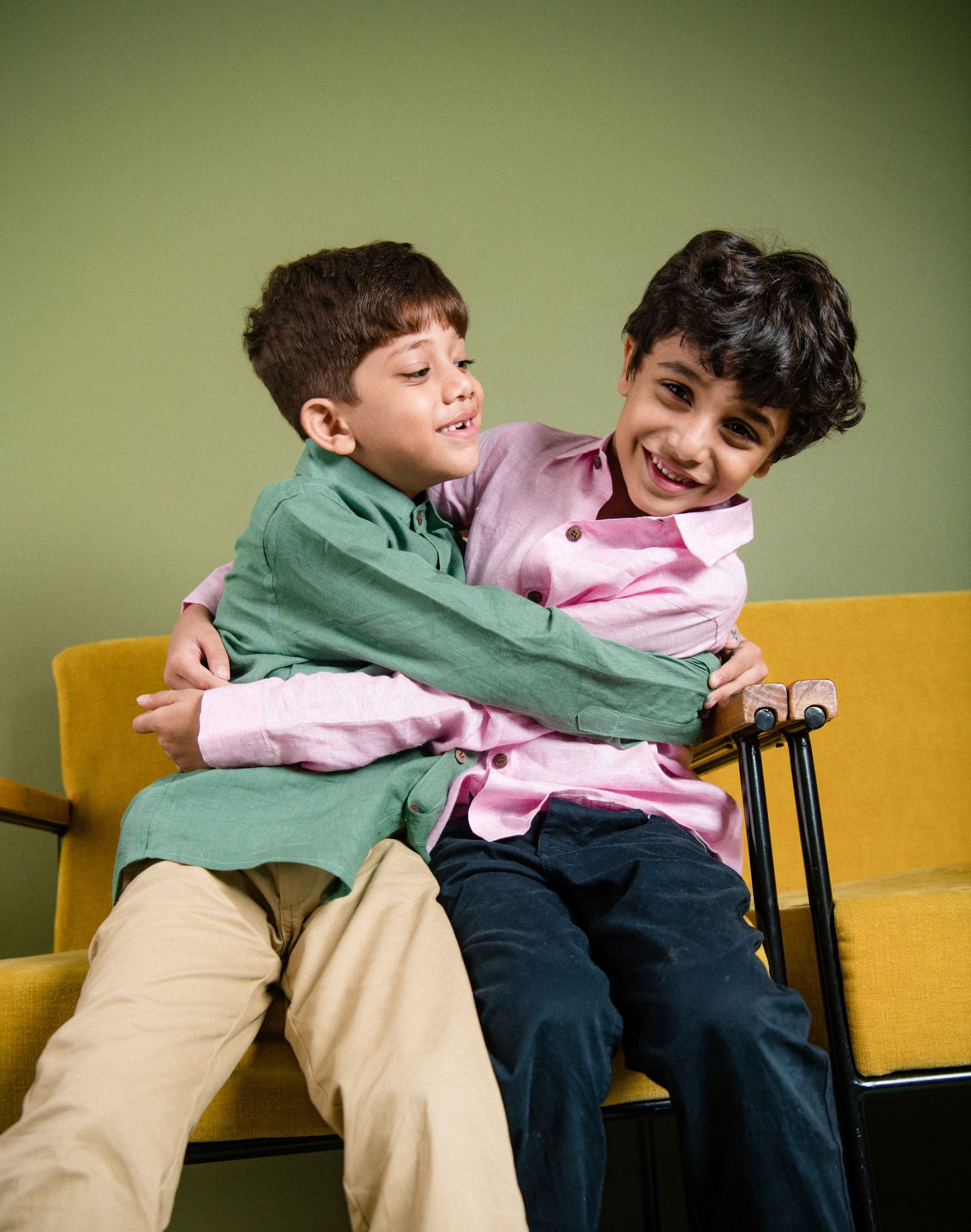 two boys in green and pink linen shirt playing with each other