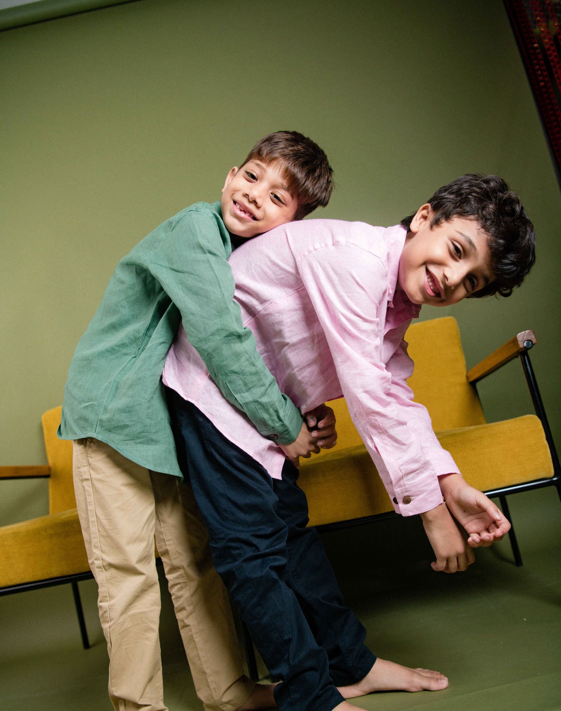 two boys in green and pink linen shirt playing with each other