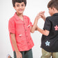 Two young boys in red and black linen shirt with roosters and flowers embroidered respectively