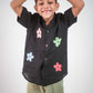 a young 5-6 year old boy in a floral black linen shirt goofing around