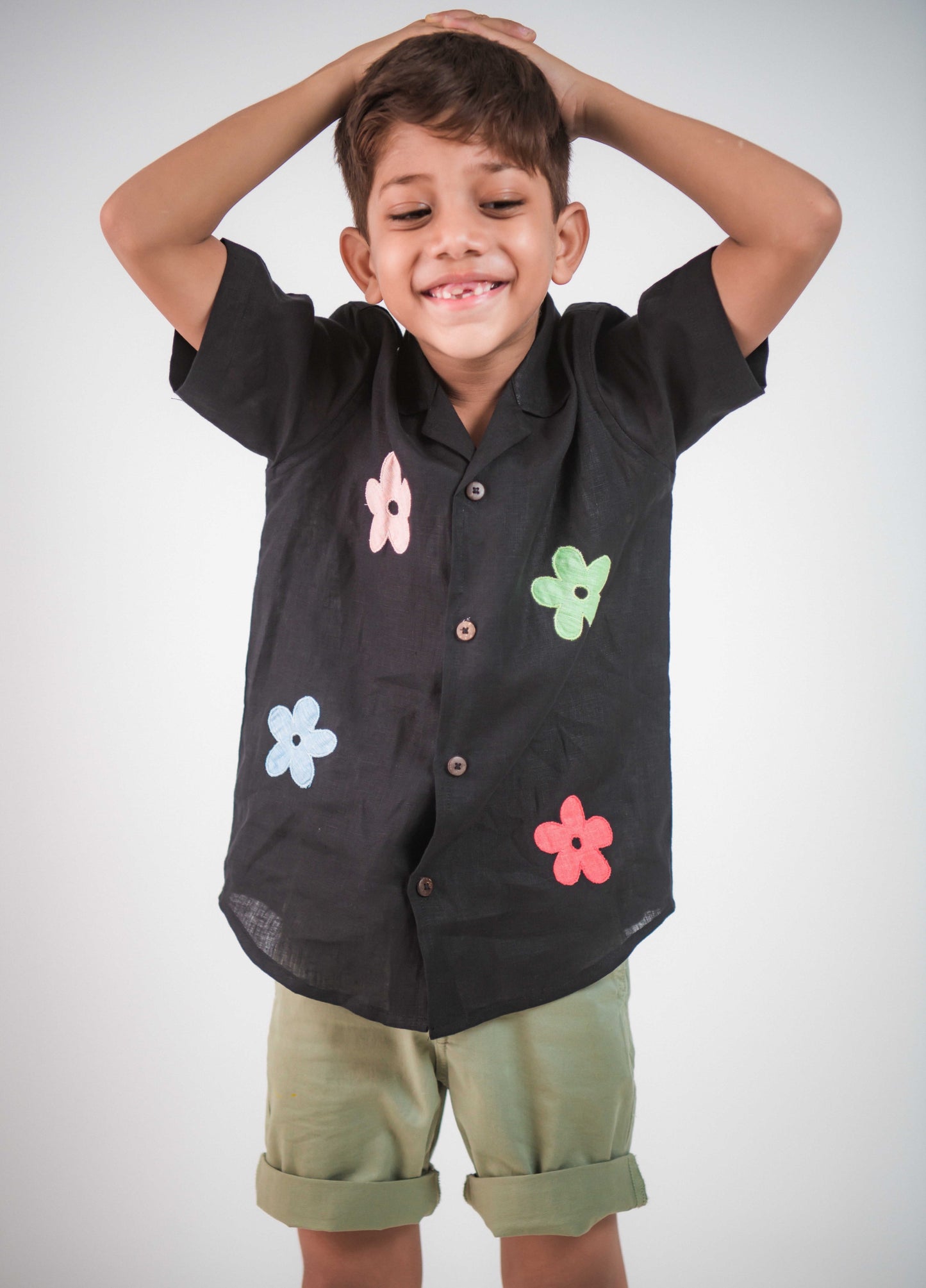 a young 5-6 year old boy in a floral black linen shirt goofing around