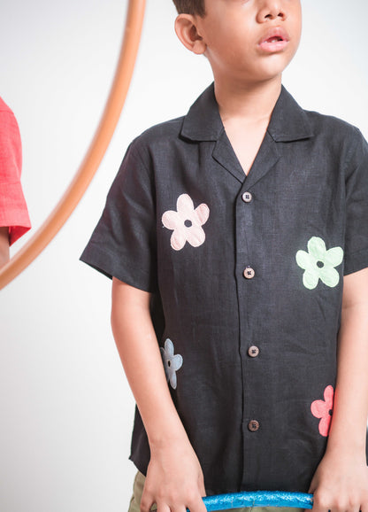 Details of a young 5-6 year old boy in a floral black linen shirt goofing around