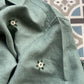 Details of  a green linen shirt with flowers embroidered throughout 