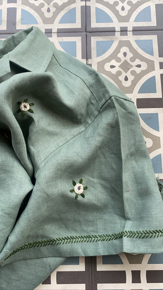 Details of  a green linen shirt with flowers embroidered throughout 