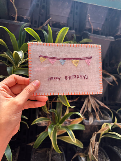 Close-up view of the intricate hand embroidery on the birthday-themed postcard, showcasing detailed stitching and vibrant colors