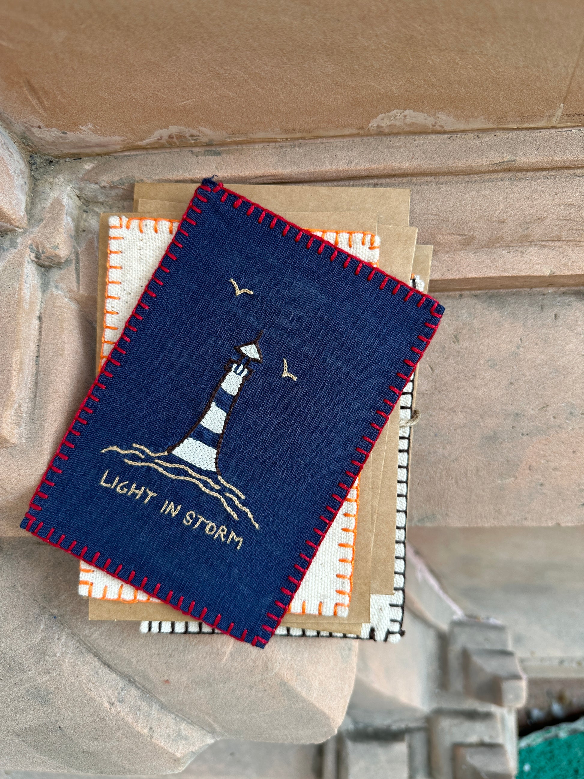 Close-up view of the intricate hand embroidery showing a lighthouse amidst stormy waves, depicting resilience and hope