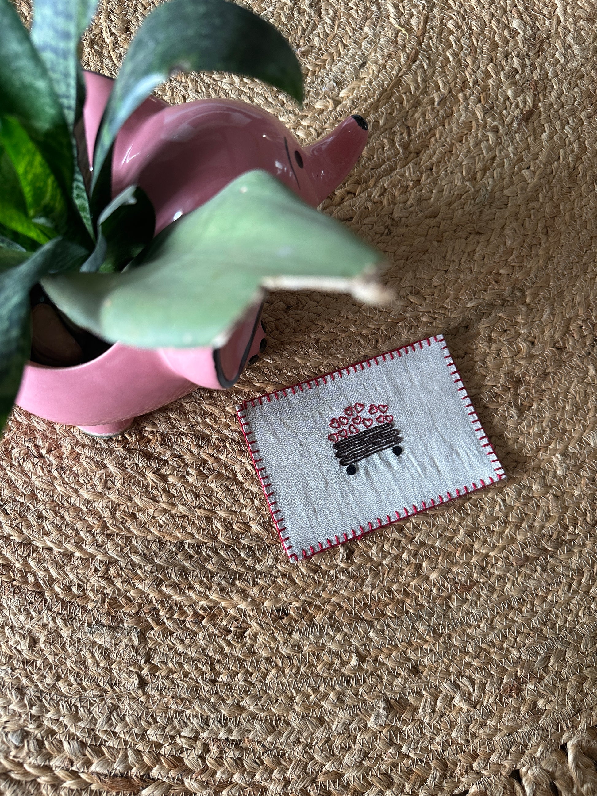 Hand-embroidered postcard featuring a small lorry filled with colorful hearts on sustainable linen, perfect for sending heartfelt greetings