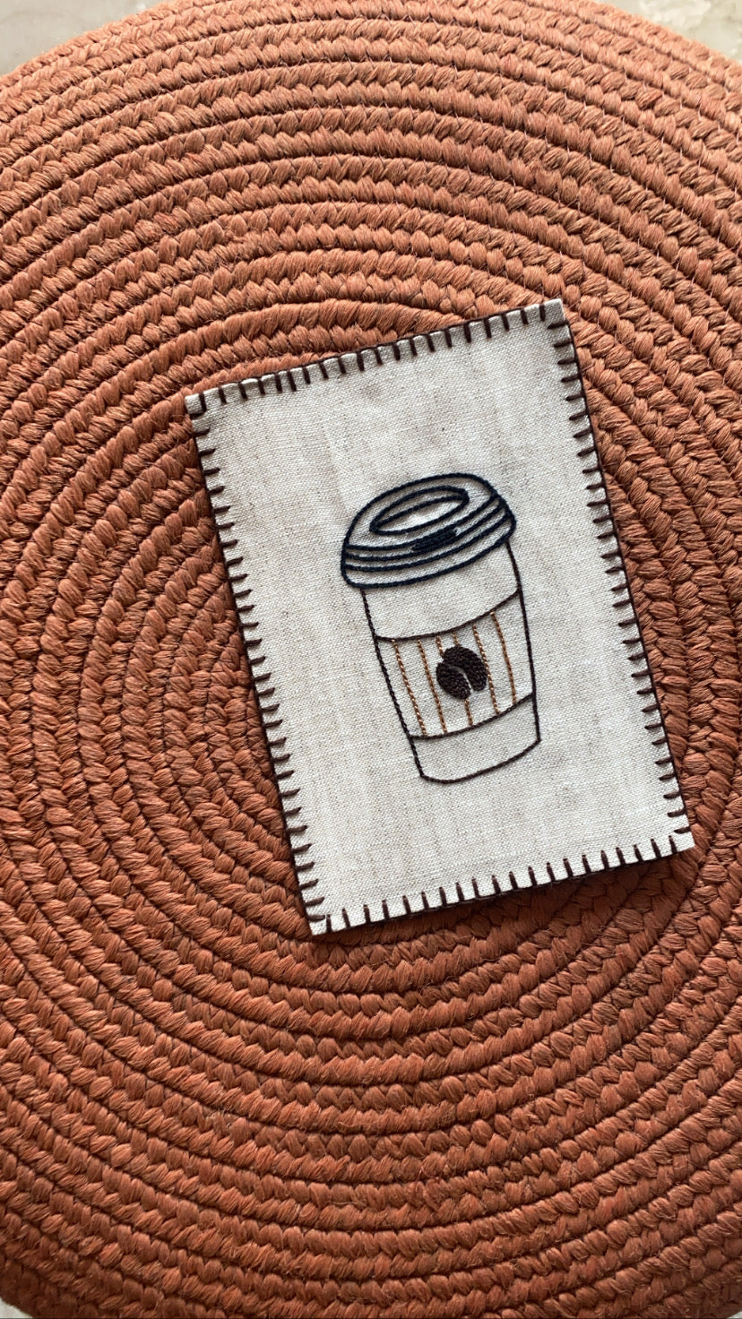 Hand-embroidered postcard depicting a steaming cup of coffee, crafted from sustainable linen, perfect for coffee lovers